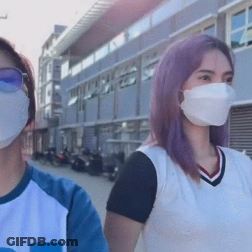 Two Women Wearing Face Masks Standing Next To Each Other In Front Of A Building GIF