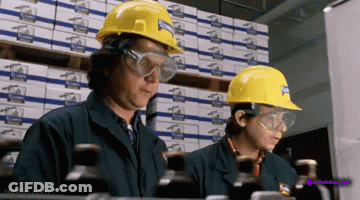 Two Women Wearing Hard Hats And Safety Goggles Are Working In A Factory GIF