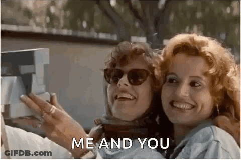 Two Women Wearing Sunglasses Are Taking A Selfie With A Polaroid Camera . GIF