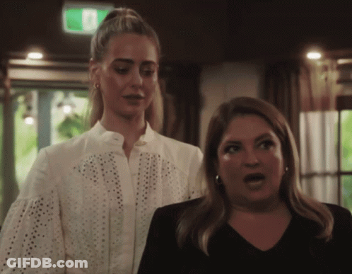 Two Women With Green Exit Sign Above GIF