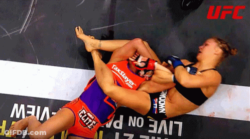 Two Women Wrestling In Front Of Live Sign GIF