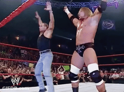 Two Wrestlers Are Dancing In A Wrestling Ring While A Crowd Watches . GIF