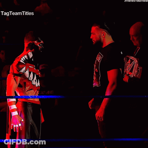 Two Wrestlers Are Facing Each Other In A Ring With The Tag Team Titles Written On The Bottom GIF