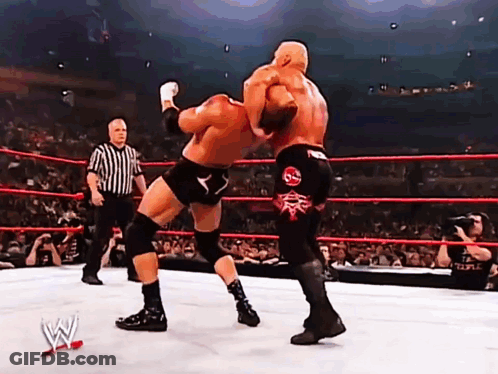 Two Wrestlers Are Fighting In A Ring With A Referee In The Background GIF