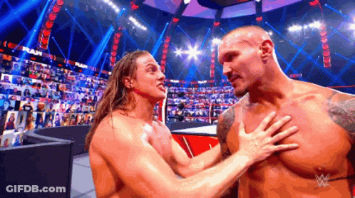 Two Wrestlers Are Hugging Each Other In A Wrestling Ring With A Crowd In The Background . GIF