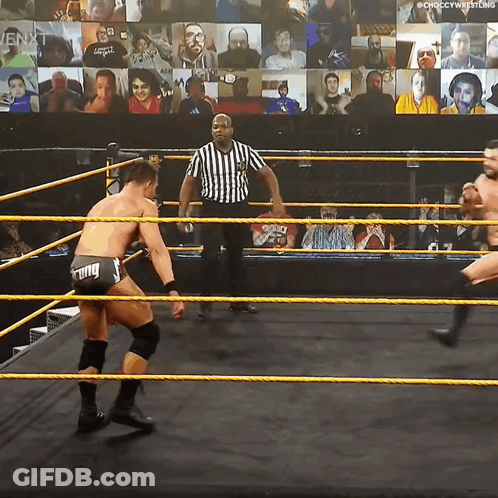 Two Wrestlers Are In A Wrestling Ring With A Referee In Front Of A Crowd GIF