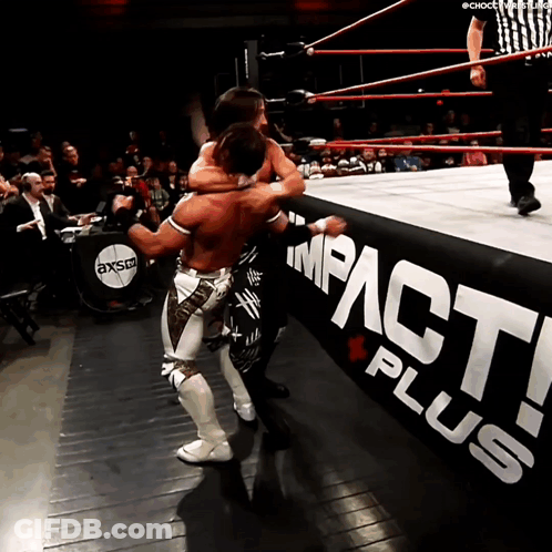 Two Wrestlers Are In A Wrestling Ring With A Sign That Says Impact Plus GIF