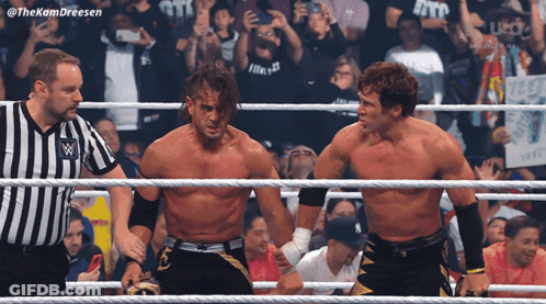 Two Wrestlers Are Standing In A Ring With A Referee And A Crowd Behind Them With The Hashtag #Thekamdreesen GIF