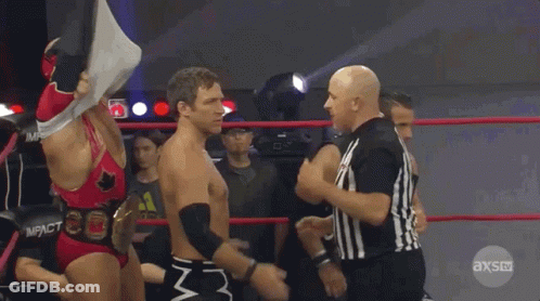 Two Wrestlers Are Standing In A Ring With A Referee In Front Of Them And The Referee Is Wearing An Axs Uniform GIF