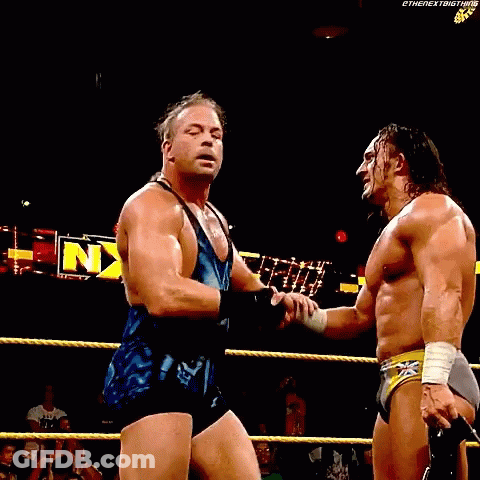 Two Wrestlers Are Standing In A Ring With Their Arms In The Air In Front Of A Sign That Says Nxt GIF