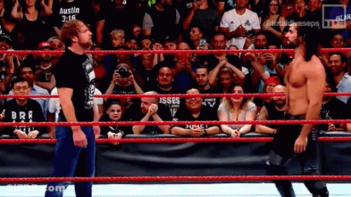 Two Wrestlers Are Standing In A Wrestling Ring With A Crowd Watching And A Banner That Says Austin 3:16 GIF