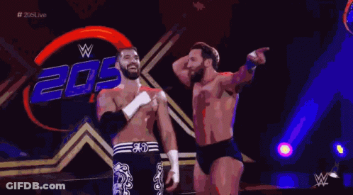 Two Wrestlers Are Standing In Front Of A Sign That Says 20 GIF