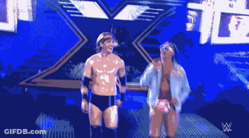 Two Wrestlers Are Standing In Front Of A Sign That Says W GIF