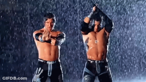 Two Wrestlers Are Standing In The Rain With Their Arms In The Air . GIF