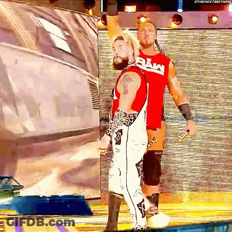 Two Wrestlers Are Standing Next To Each Other And One Of Them Is Wearing A Raw Shirt GIF
