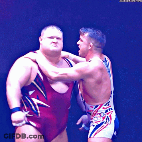 Two Wrestlers Are Standing Next To Each Other And One Of Them Is Wearing A Red And Gold Wrestling Outfit GIF