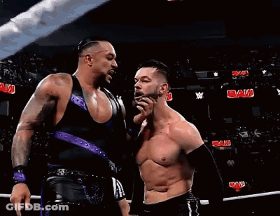Two Wrestlers Are Standing Next To Each Other In A Ring . GIF