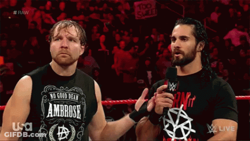 Two Wrestlers Are Standing Next To Each Other In A Wrestling Ring And One Of Them Is Wearing A Shirt That Says Ambrose GIF