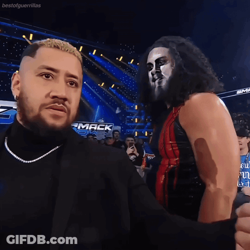 Two Wrestlers Are Standing Next To Each Other In Front Of A Sign That Says " Mack " GIF