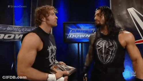 Two Wrestlers Are Standing Next To Each Other In Front Of A TV Screen . GIF