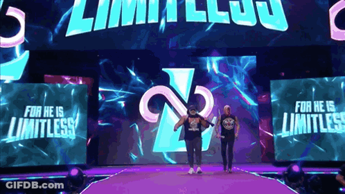 Two Wrestlers Are Walking Down A Purple Ramp With The Words For He Is Limitless On The Screen Behind Them GIF