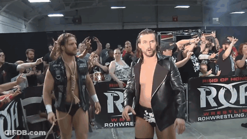 Two Wrestlers Are Walking In Front Of A Sign That Says Ring Of Honor GIF