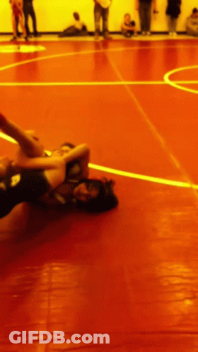Two Wrestlers Are Wrestling On A Red Mat With A Yellow Line GIF