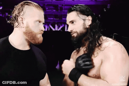 Two Wrestlers Beside Sign Saying Nxtl GIF