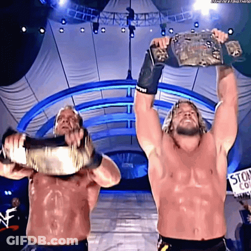 Two Wrestlers Holding Up Championship Belts GIF
