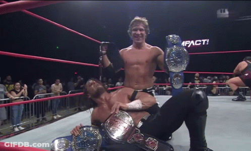 Two Wrestlers In A Ring With A Sign That Says Impact In The Background GIF