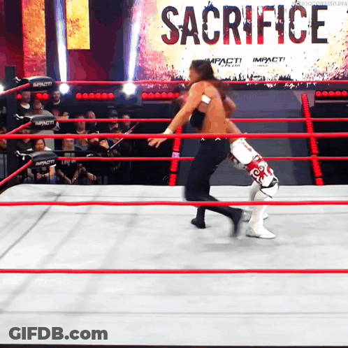 Two Wrestlers In A Ring With A Sign That Says Sacrifice On It GIF