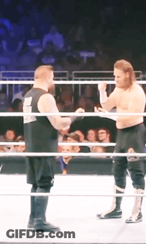 Two Wrestlers In A Ring With One Wearing A Shirt That Says ' Smackdown ' GIF