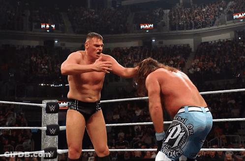 Two Wrestlers In A Wrestling Ring With One Wearing A Pair Of Shorts With The Letter P On Them GIF