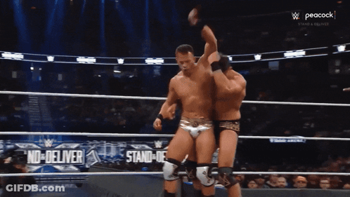 Two Wrestlers In Ring With Peacock Ad GIF