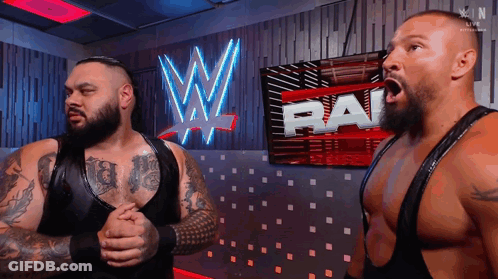 Two Wrestlers Standing In Front Of WWE Sign GIF