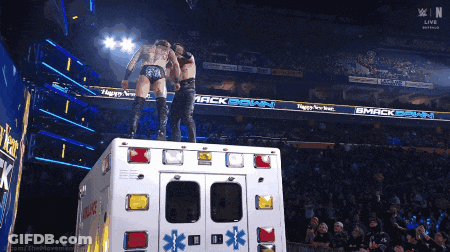 Two Wrestlers Standing On Ambulance Saying Smackdown GIF