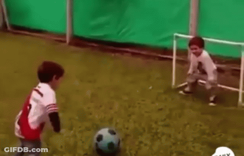 Two Young Boys Are Playing Soccer On A Soccer Field With A Goal . GIF