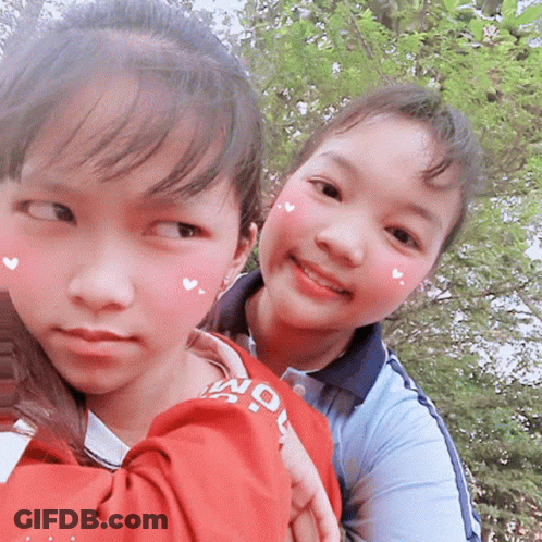 Two Young Girls Are Posing For A Picture With One Wearing A Shirt That Says " Seoul " GIF