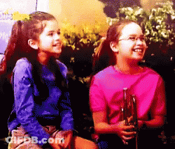 Two Young Girls Are Sitting Next To Each Other And One Is Wearing A Pink Shirt GIF