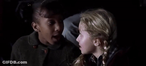 Two Young Girls Sitting Next To Each Other In Dark Room GIF