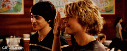 Two Young Men Are Giving Each Other A High Five GIF