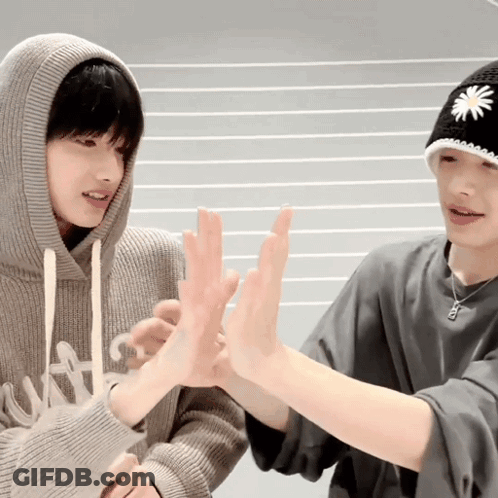 Two Young Men Are Giving Each Other A High Five While Wearing Hats . GIF
