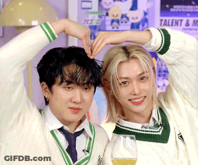 Two Young Men Are Making A Heart Shape With Their Hands In Front Of A Poster That Says Talent GIF