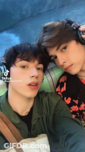 Two Young Men Are Posing For A Picture And One Of Them Has Tiktok Written On His Phone GIF