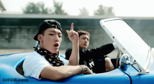 Two Young Men Are Sitting In A Blue Convertible Car And One Of Them Is Giving The Middle Finger GIF
