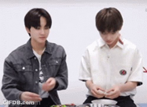 Two Young Men Are Sitting Next To Each Other And Playing With A Toy . GIF