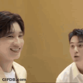 Two Young Men Are Sitting Next To Each Other And Smiling At Each Other . GIF
