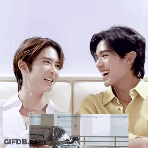 Two Young Men Are Sitting Next To Each Other And Smiling GIF