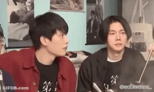 Two Young Men Are Sitting Next To Each Other In A Living Room . GIF