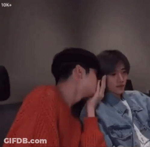 Two Young Men Are Sitting Next To Each Other In A Room And Holding Hands . GIF